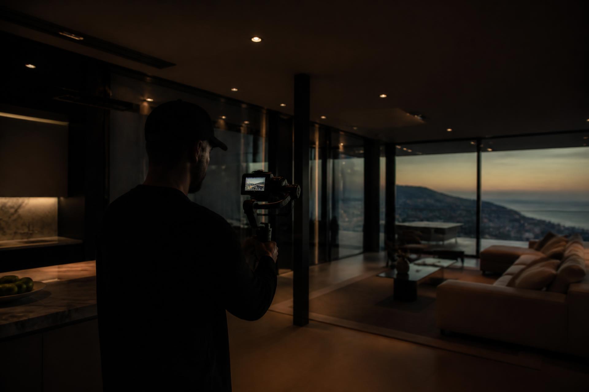 Videographer filming inside a luxury modern home at dusk